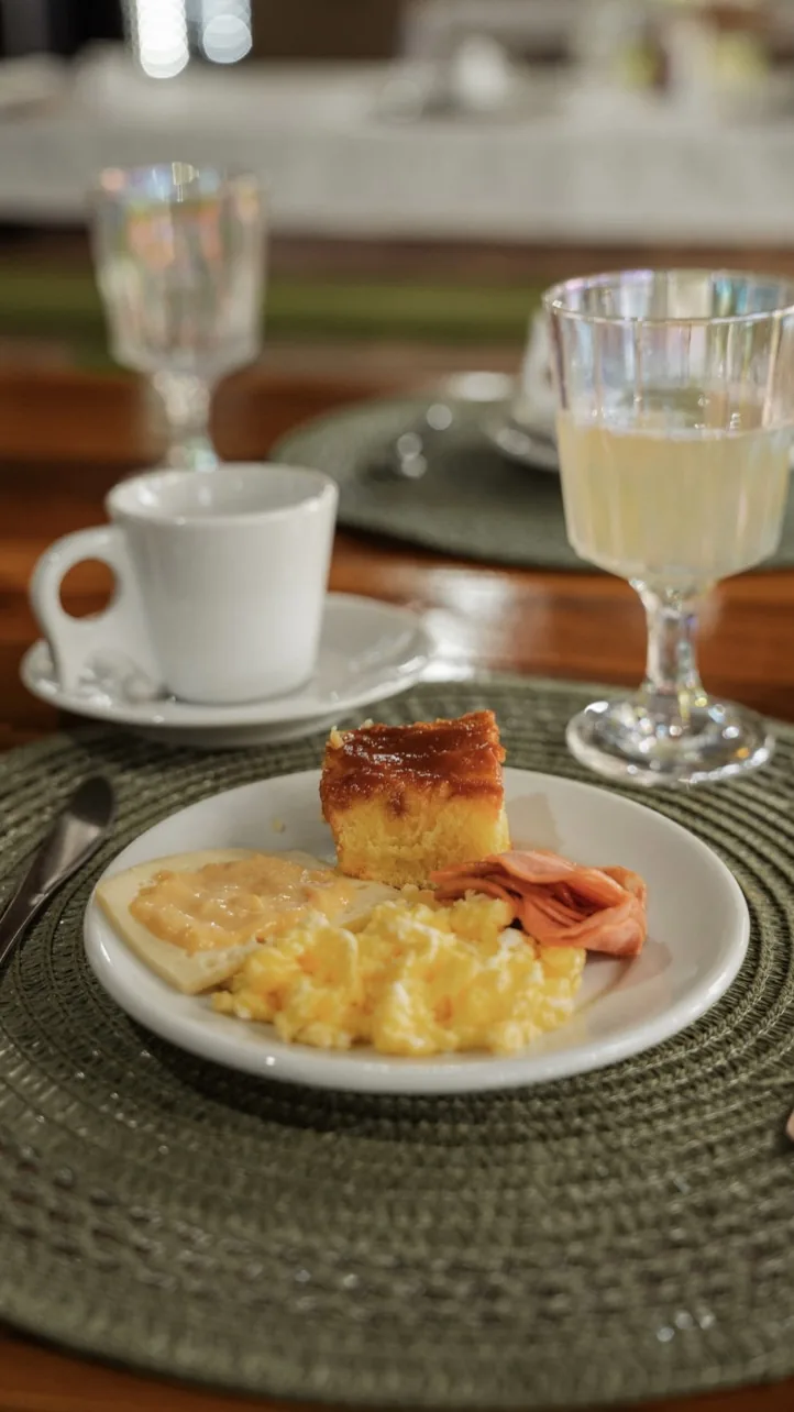 Mesa de café da manhã com ovos mexidos, bolo, suco e café
