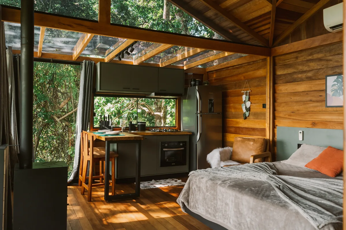 Interior de madeira do Chalé Casa na Árvore, com cama e cozinha